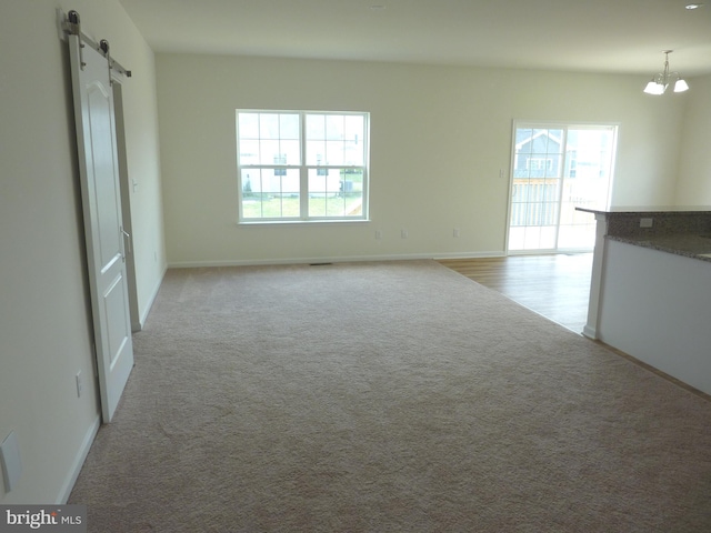 interior space featuring a barn door, light colored carpet, and a chandelier