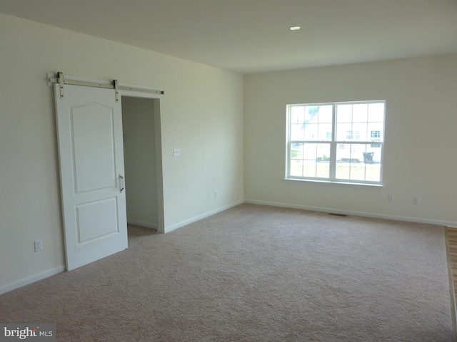 carpeted spare room featuring a barn door