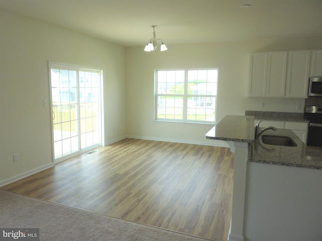 kitchen featuring hardwood / wood-style floors, stone counters, sink, stainless steel appliances, and a chandelier