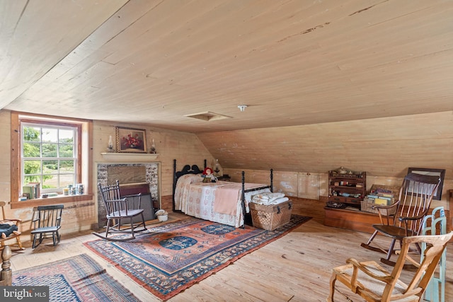 bedroom featuring light hardwood / wood-style floors, a fireplace, wooden ceiling, and lofted ceiling