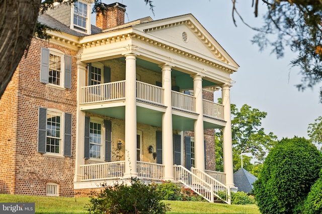 view of front facade with a front yard and a balcony