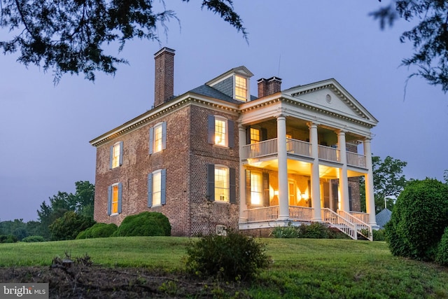 greek revival house with a balcony and a lawn