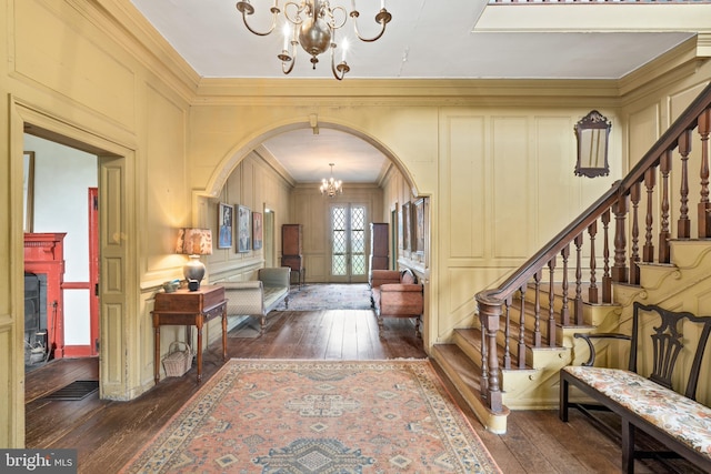 foyer with french doors, dark wood-type flooring, an inviting chandelier, and ornamental molding