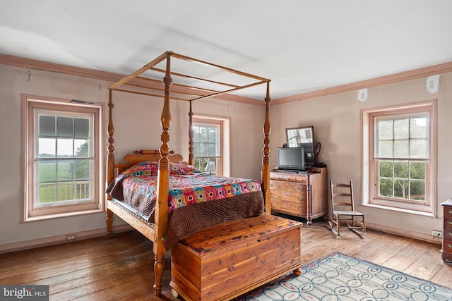 bedroom featuring crown molding, light wood-type flooring, and multiple windows