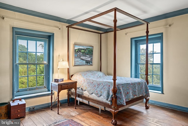 bedroom with light hardwood / wood-style flooring, crown molding, and multiple windows