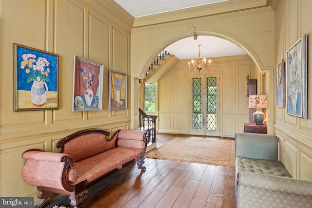 entryway with ornamental molding, a notable chandelier, and wood-type flooring