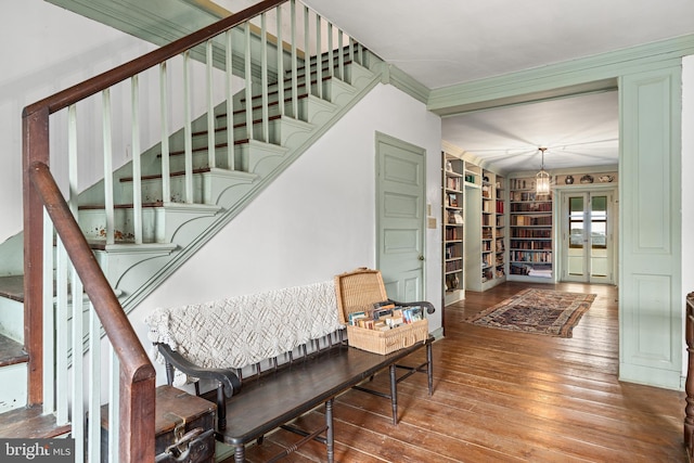 interior space featuring french doors, crown molding, built in features, dark hardwood / wood-style floors, and a chandelier