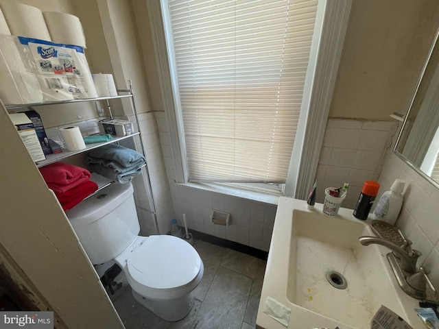 bathroom featuring sink, tile flooring, toilet, and tile walls