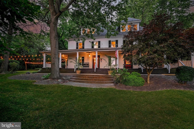 back house at dusk with a yard and a porch