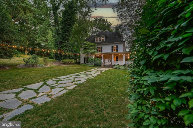 yard at dusk featuring covered porch