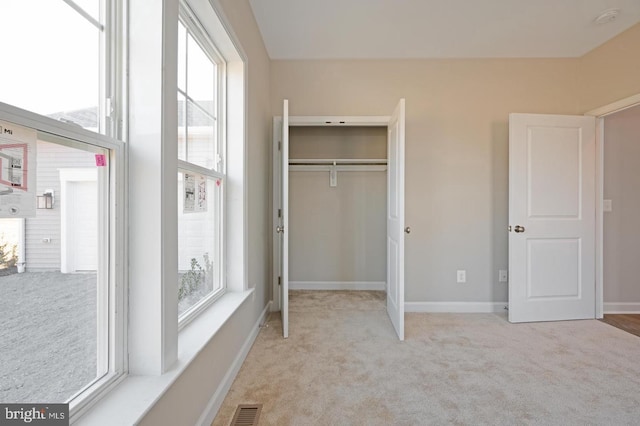 unfurnished bedroom featuring light colored carpet and a closet