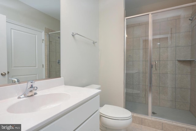 bathroom featuring a shower with shower door, toilet, and vanity