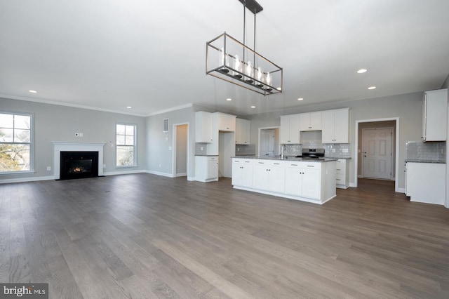 kitchen featuring tasteful backsplash, hardwood / wood-style floors, white cabinets, and ornamental molding