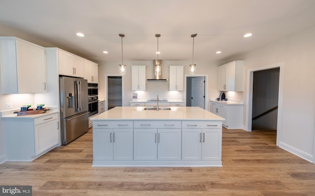 kitchen featuring a center island with sink, pendant lighting, white cabinetry, light wood-type flooring, and appliances with stainless steel finishes