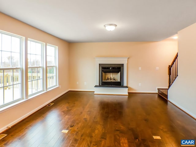 unfurnished living room featuring a wealth of natural light and dark hardwood / wood-style flooring