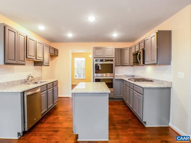 kitchen with dark wood-type flooring, stainless steel appliances, gray cabinetry, a center island, and sink