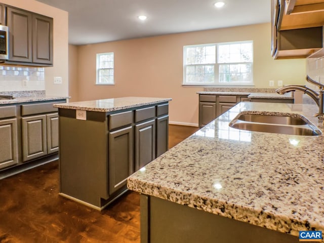 kitchen with a kitchen island, plenty of natural light, and light stone countertops