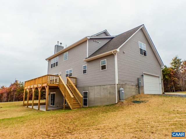 rear view of property with a wooden deck, a patio, a garage, and a yard