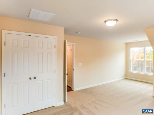 unfurnished bedroom featuring light carpet and a closet