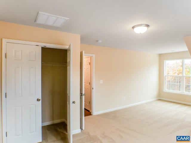 unfurnished bedroom featuring light colored carpet and a closet