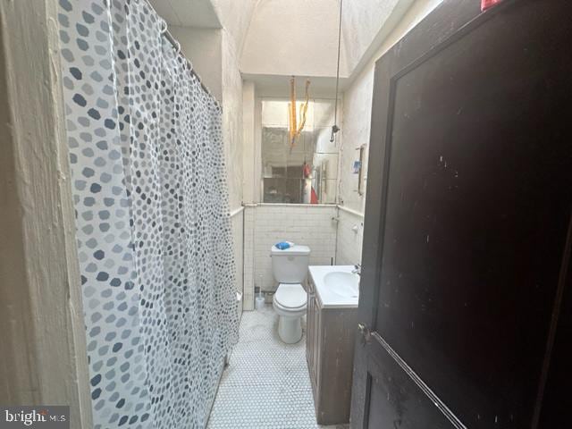 bathroom featuring tile walls, toilet, and vanity