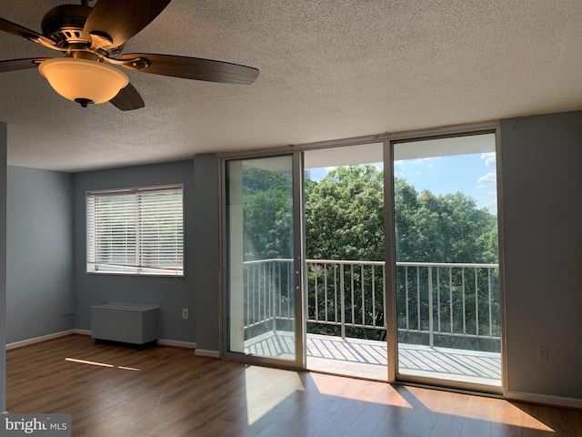 doorway to outside with dark hardwood / wood-style flooring, ceiling fan, plenty of natural light, and a textured ceiling