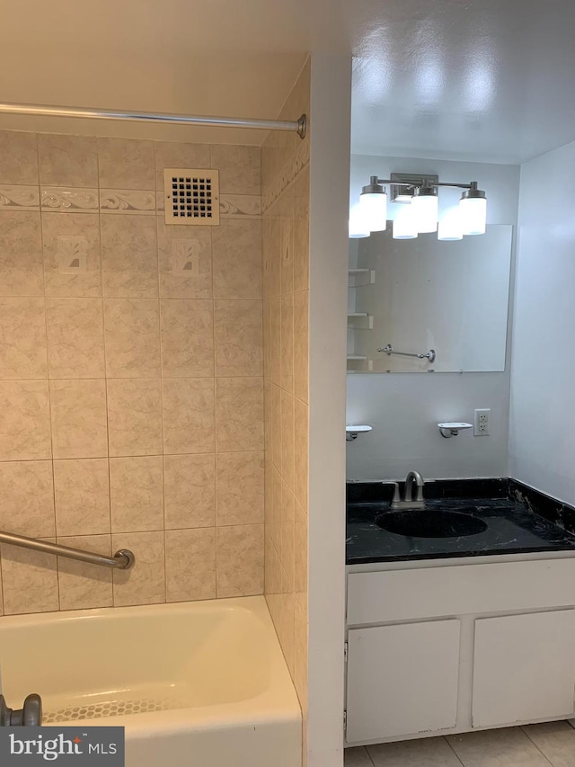 bathroom featuring tile floors, vanity, and tiled shower / bath