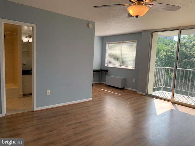 spare room featuring a textured ceiling, ceiling fan, and light wood-type flooring