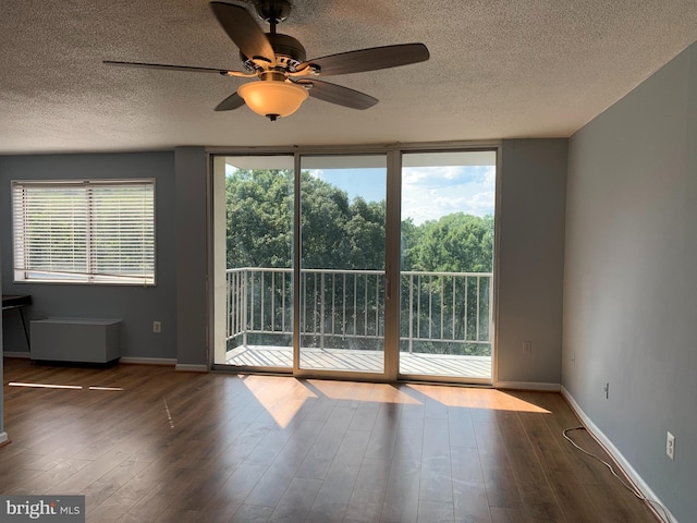 spare room with dark hardwood / wood-style flooring, ceiling fan, and a wealth of natural light