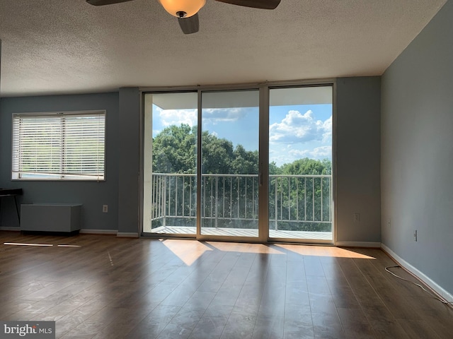 spare room with dark hardwood / wood-style flooring, ceiling fan, a textured ceiling, and expansive windows