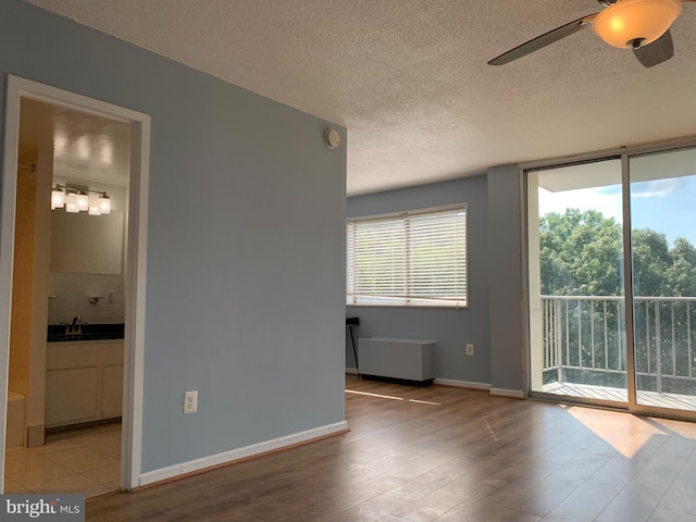 spare room featuring a textured ceiling, ceiling fan, sink, and light wood-type flooring