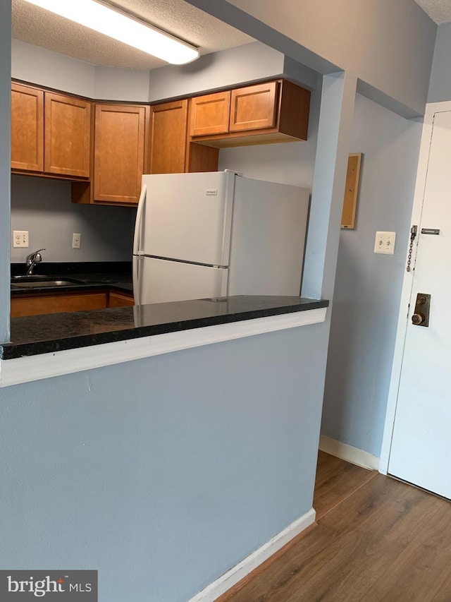 kitchen with dark hardwood / wood-style flooring, a textured ceiling, sink, and white fridge