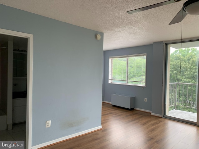 unfurnished room with a textured ceiling, ceiling fan, and light wood-type flooring