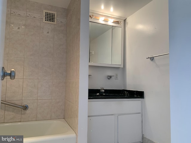 bathroom featuring tiled shower / bath and vanity