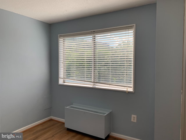 unfurnished room featuring plenty of natural light, a textured ceiling, and dark wood-type flooring