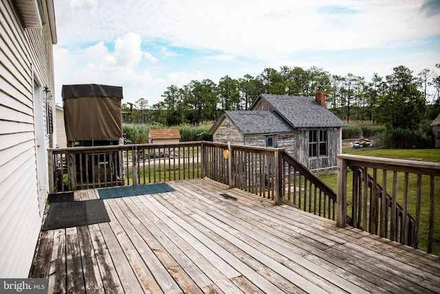 wooden terrace featuring an outdoor structure and a yard