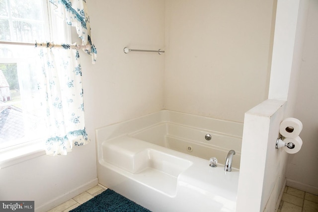 bathroom featuring tile flooring, a bathtub, and a healthy amount of sunlight