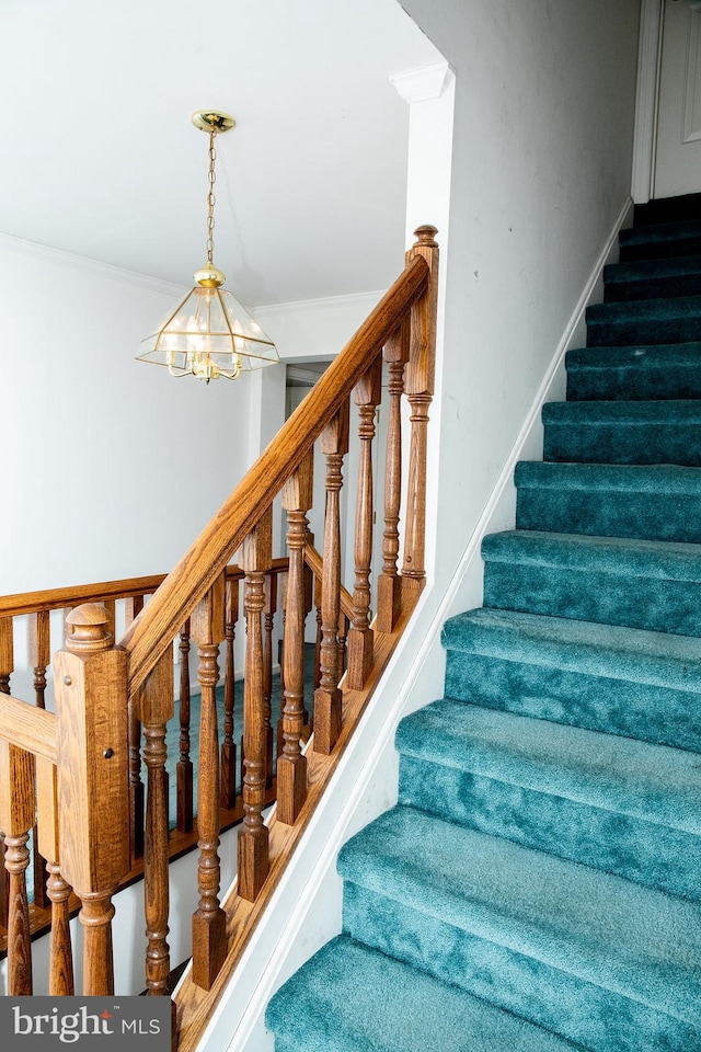 stairway with ornamental molding and a notable chandelier