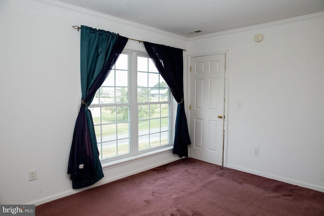 spare room with dark colored carpet, crown molding, and a healthy amount of sunlight