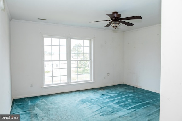 carpeted spare room featuring ceiling fan, a wealth of natural light, and ornamental molding