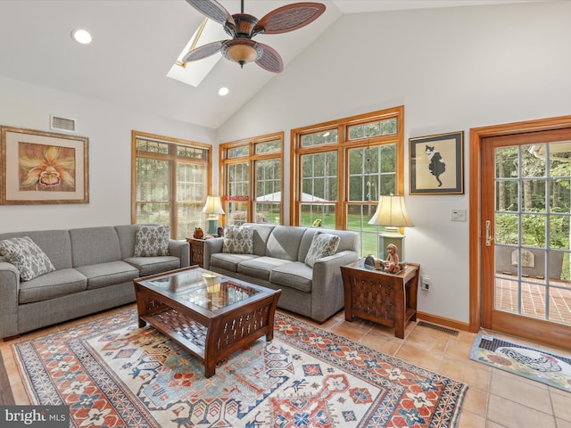 tiled living room with high vaulted ceiling, ceiling fan, and a skylight