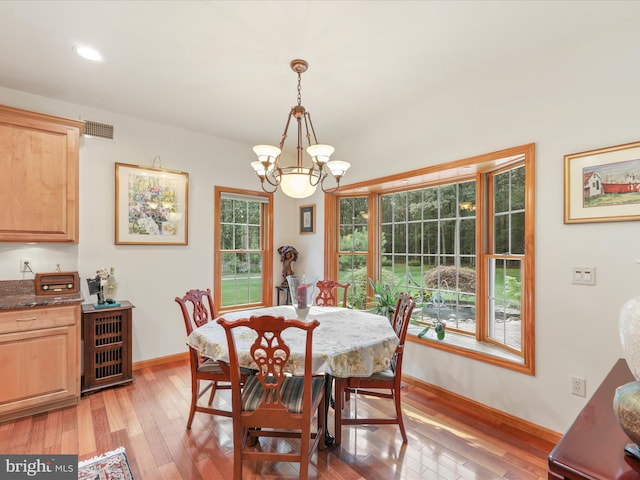 dining space featuring light wood-type flooring, plenty of natural light, and a chandelier