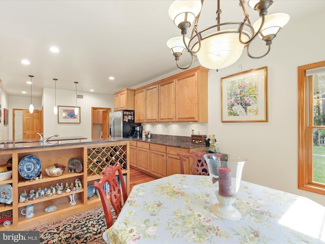 dining space with light hardwood / wood-style flooring, sink, and a chandelier