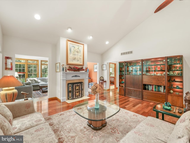 living room featuring high vaulted ceiling and light wood-type flooring