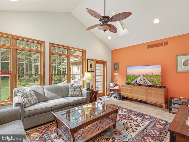 tiled living room with plenty of natural light, high vaulted ceiling, ceiling fan, and a skylight