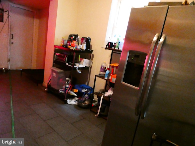 interior space with dark tile floors and stainless steel fridge