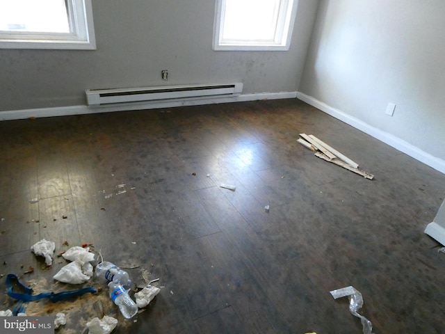 spare room with dark wood-type flooring and a baseboard heating unit