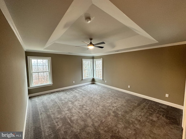 carpeted spare room featuring a tray ceiling, baseboards, a ceiling fan, and crown molding