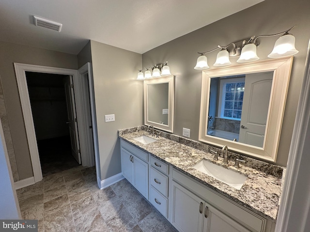 full bathroom featuring a sink, visible vents, baseboards, and double vanity