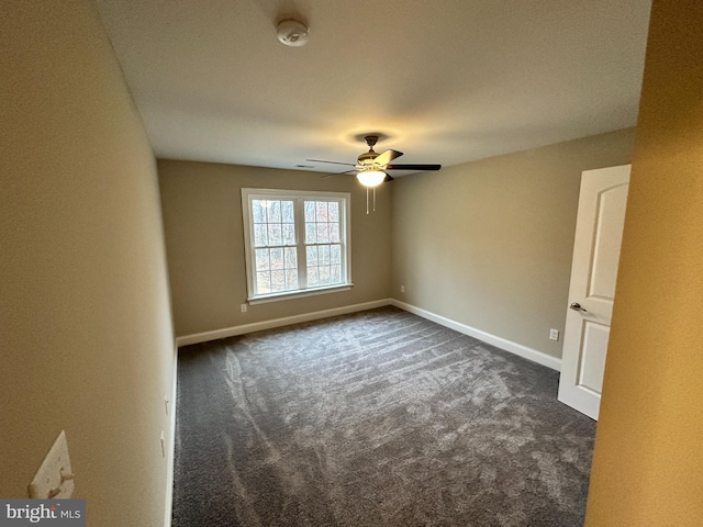 unfurnished room featuring a ceiling fan, baseboards, and dark colored carpet